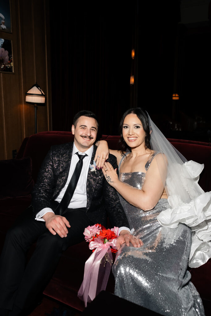 Couple relaxing together on a lounge sofa inside the NoMad Library after their Las Vegas micro wedding ceremony.
