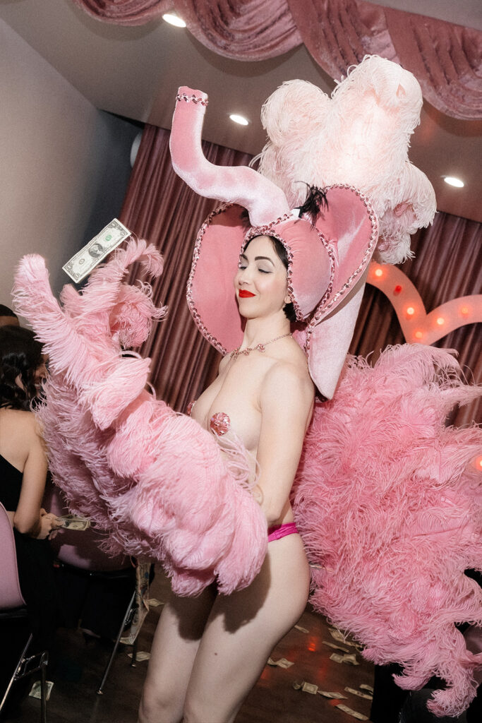 Surely the Showgirl holding dollar bills mid-performance during a playful Las Vegas micro wedding celebration at Sure Thing Chapel.