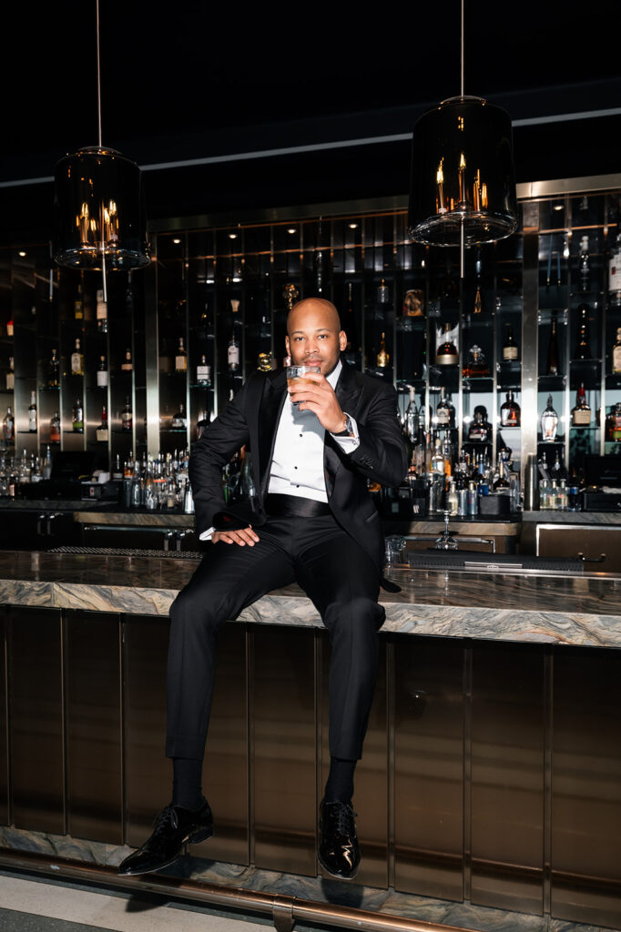 Groom posing on a bar countertop for his Wynn Las Vegas wedding portraits.