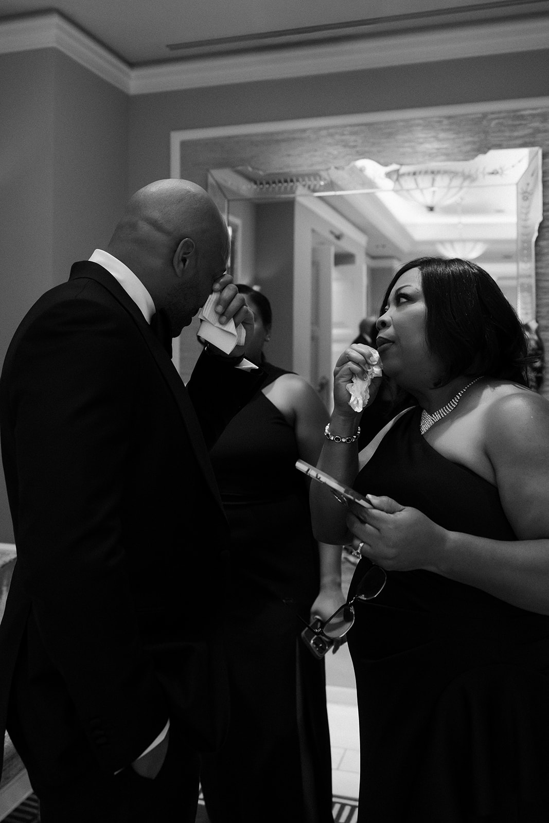 Black and white candid photo of a groom getting emotional with his family before the ceremony.