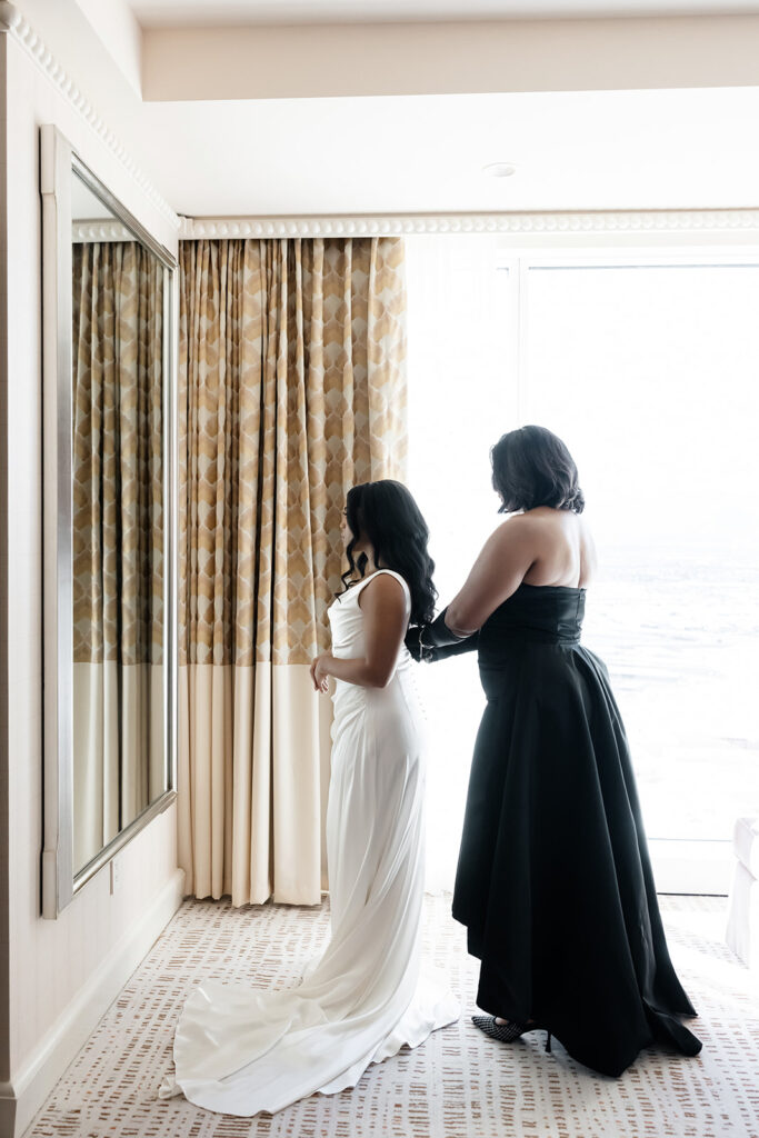 Brides mother helping her into her wedding dress.