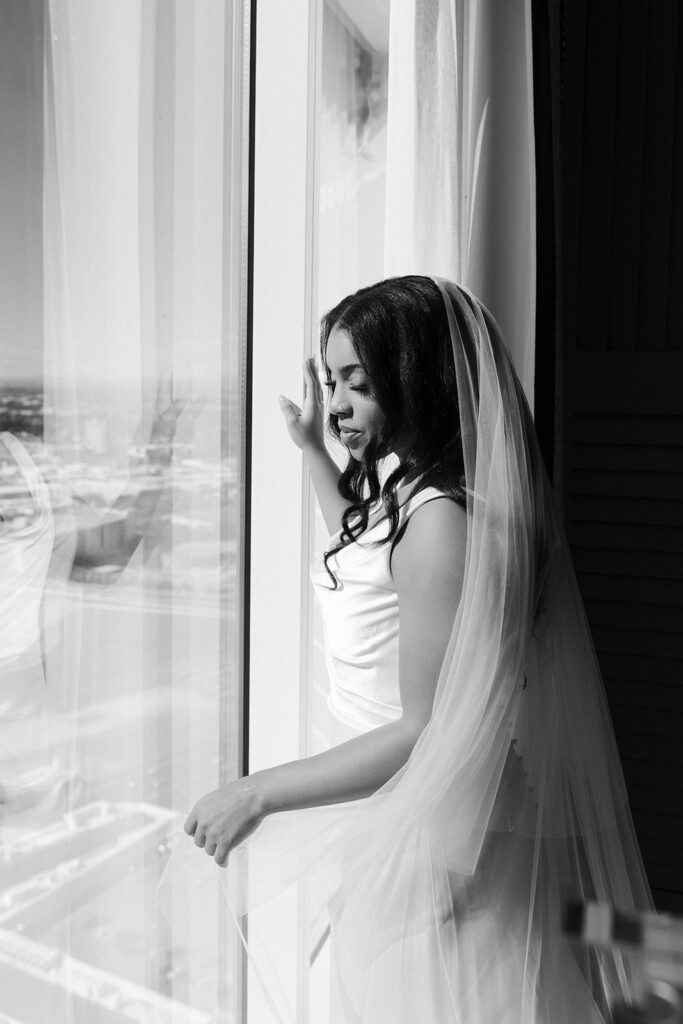 Black and white photo of a bride looking out at the city of Vegas for her Wynn hotel suite.