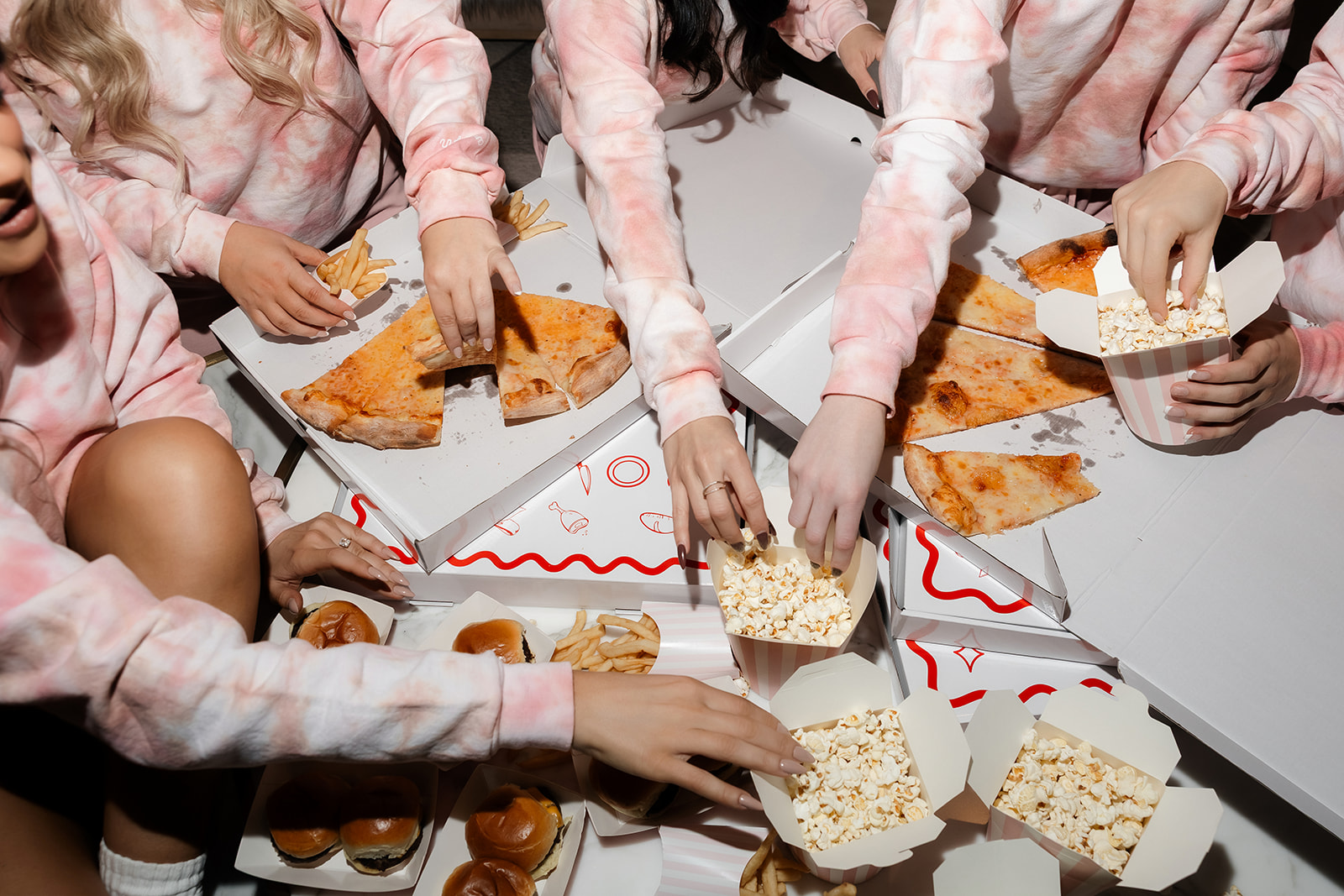Bride-to-be and friends eating pizza and fries during cozy Las Vegas bachelorette party night in.