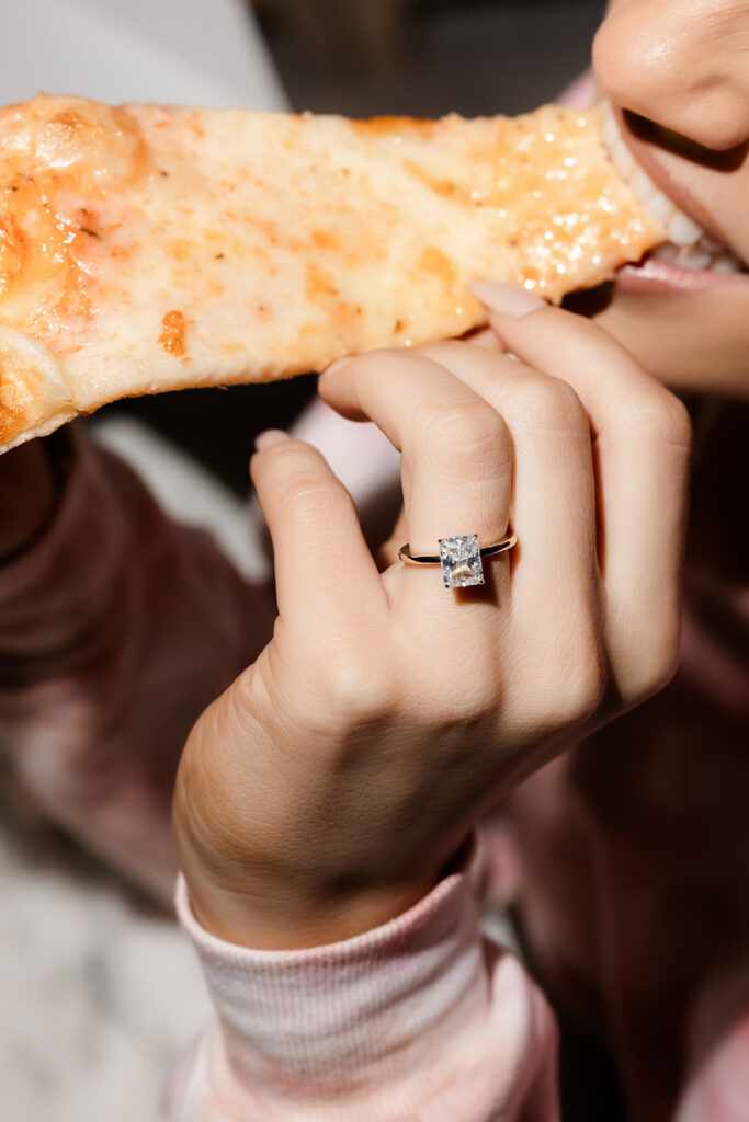 Bride-to-be holding slice of pizza during relaxed Las Vegas bachelorette party in hotel suite.