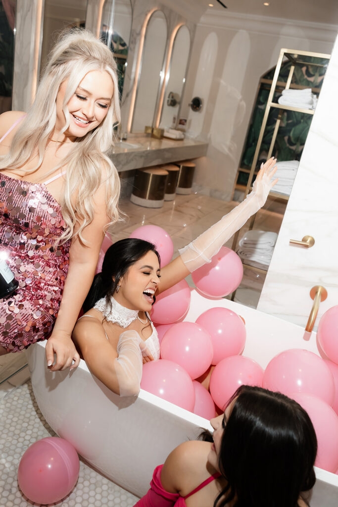 Bride posing inside of a bathtub filled with pink balloons for her Las Vegas bachelorette party photos.