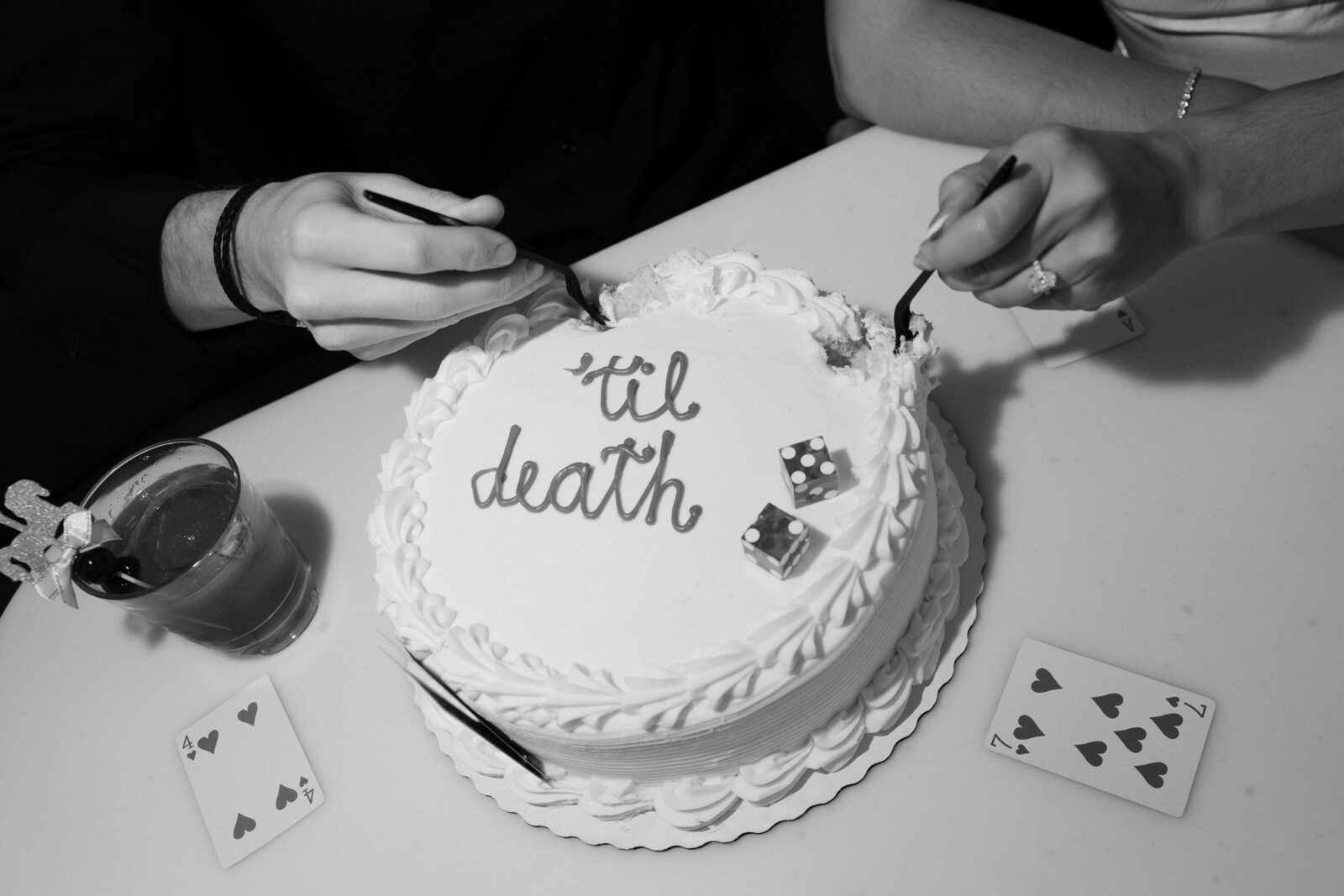 Black and white photo of a couple digging into their Las Vegas engagement cake for their photos.