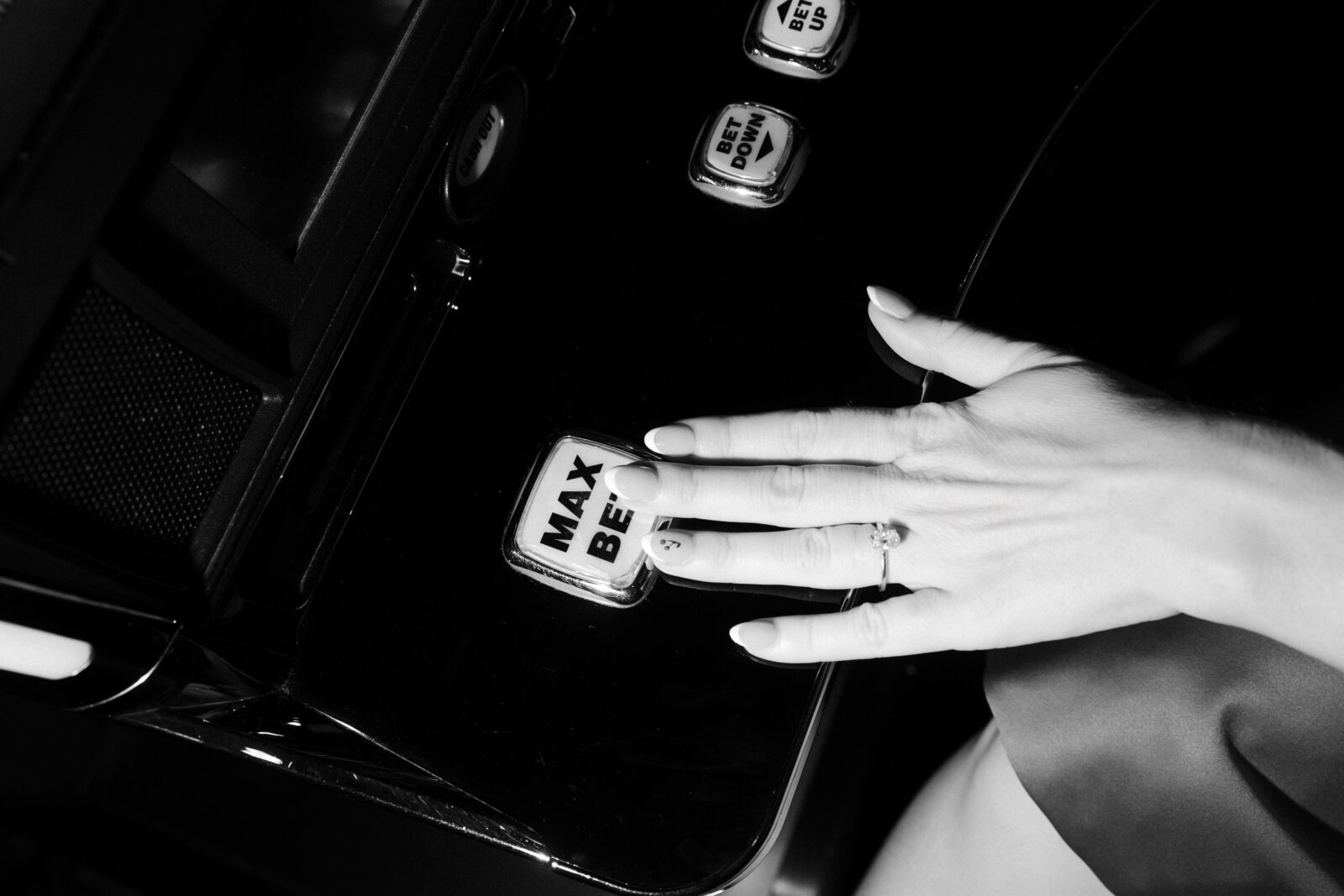 Black and white photo of a woman hitting max bet and showing off her engagement ring during her Las Vegas engagement photos at the casino.