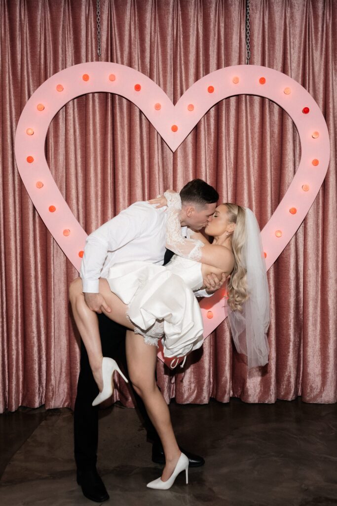 Couple kissing in front of the pink heart at Sure Thing Chapel in Las Vegas.
