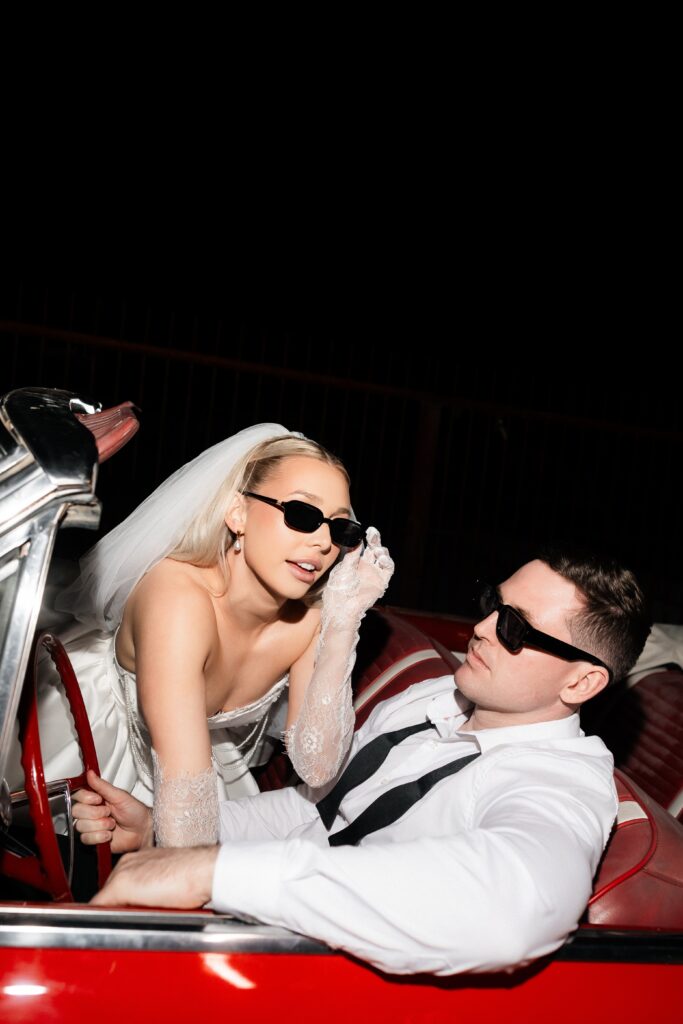 Flash engagement photo of a couple posing in a red convertible at night for their Las Vegas engagement. 