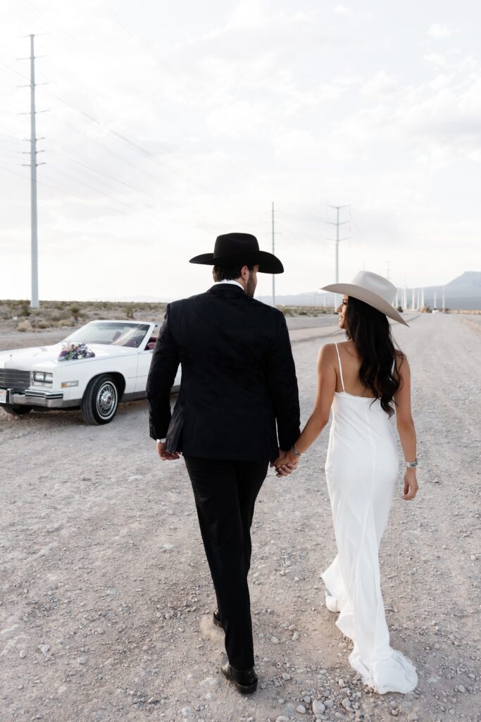 Couple holding hands and walking in the desert for their Las Vegas engagement photos. 