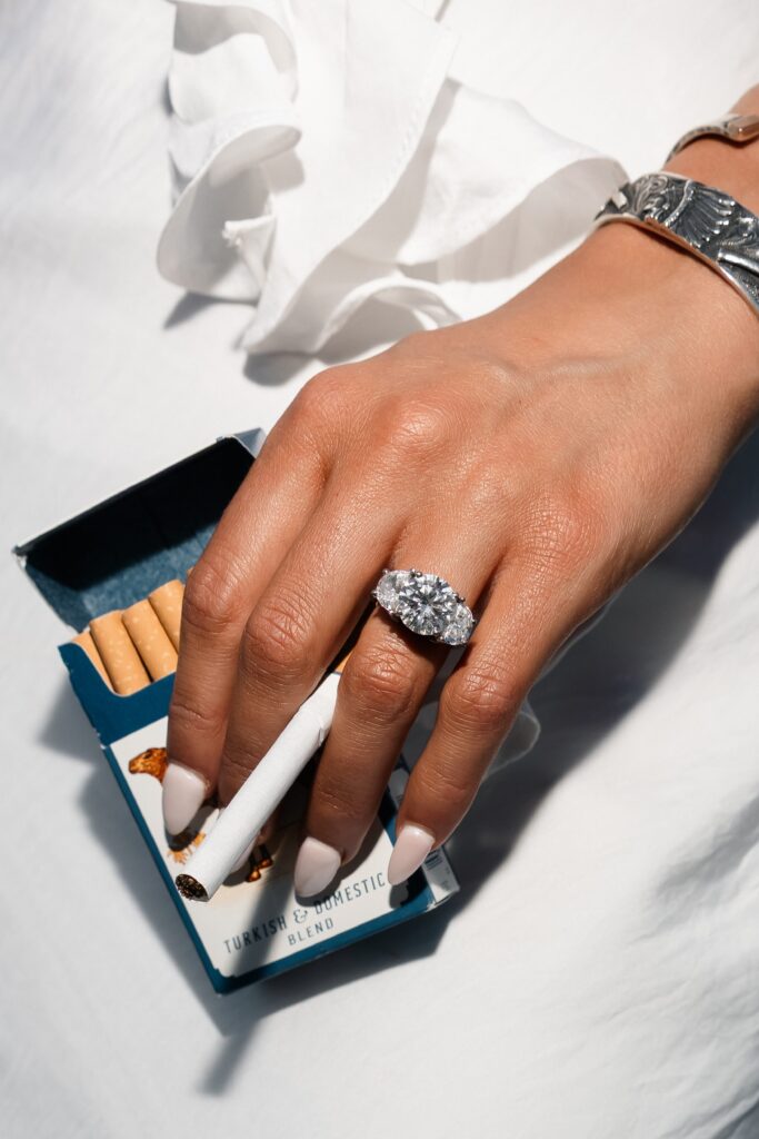 Close up flash photo of a bride to be holding a pack of Camel cigarettes and showing off her engagement ring..