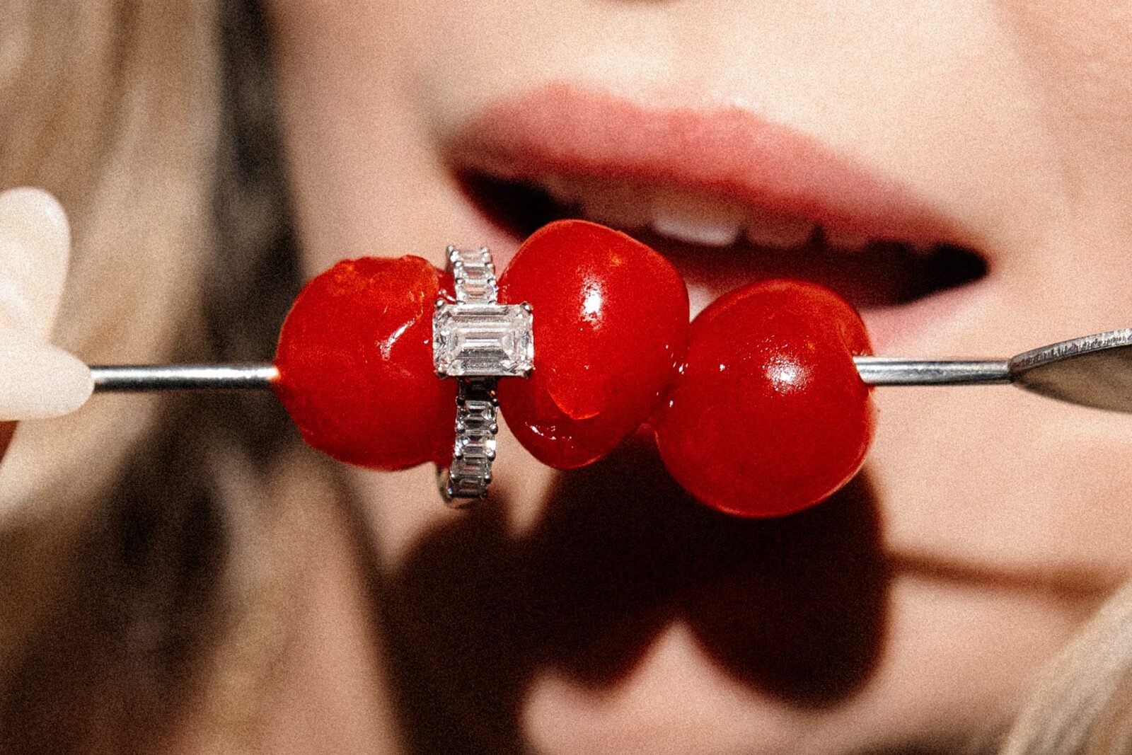 An engagement ring resting on cherries for an editorial engagement session