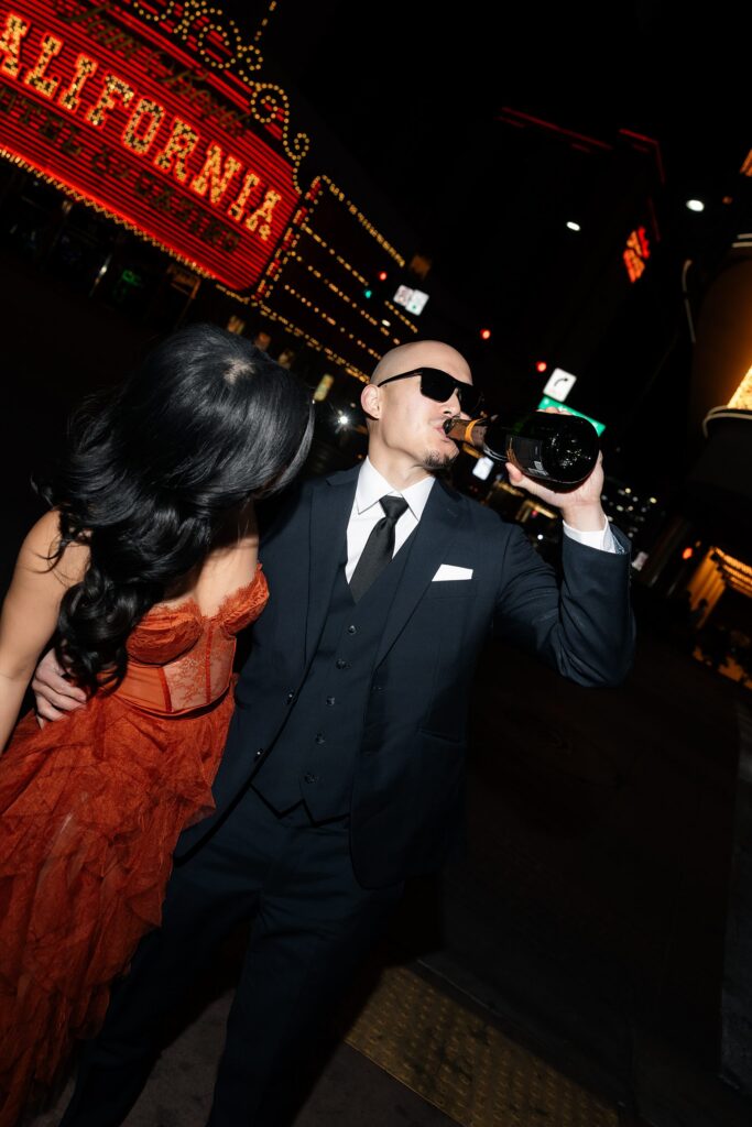 Couple drinking champagne on Fremont Street during their Las Vegas engagement photos.