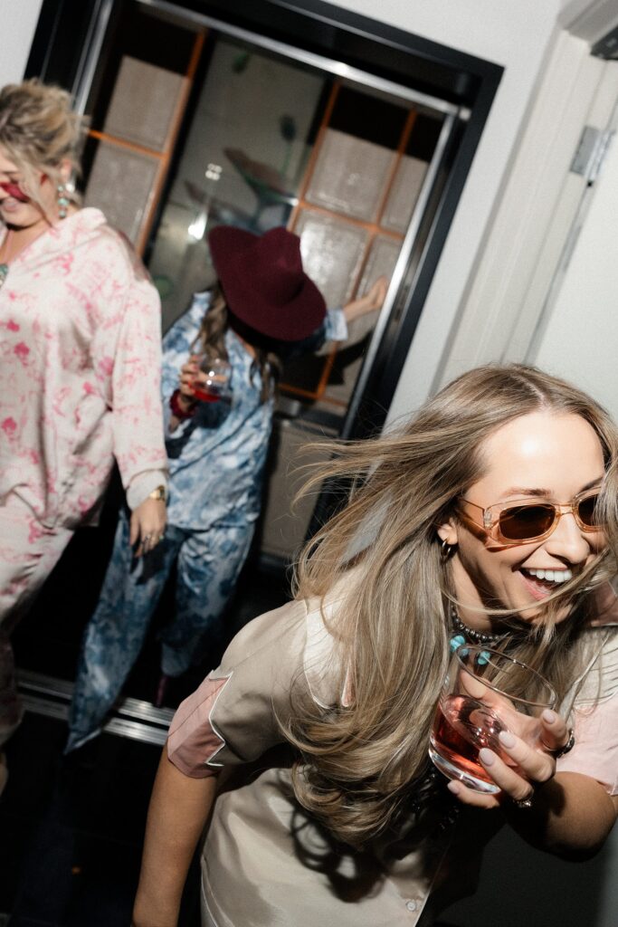 Candid photo of a bride and her friends laughing as they get off the hotel elevator. 