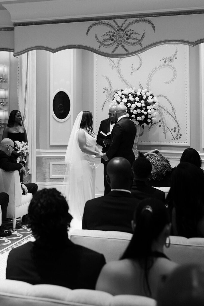 Black and white photo of a bride holding hands at the altar during their Wynn Las Vegas wedding ceremony in the Lavender Salon.