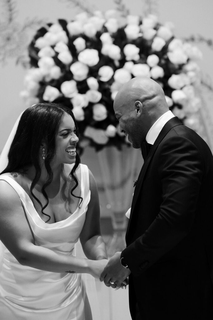 Black and white candid photo of a bride and groom laughing after their Wynn Las Vegas wedding ceremony. 
