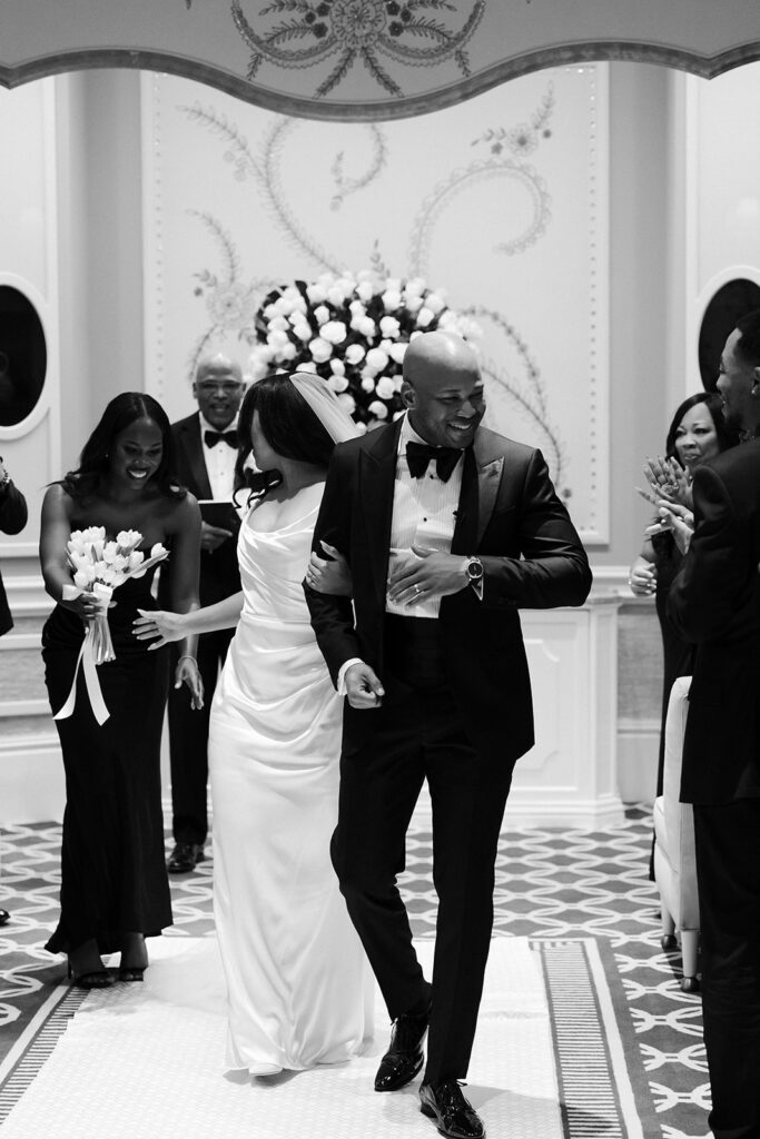 Black and white photo of a bride and groom walking back down the aisle as husband and wife after their Wynn Las Vegas wedding ceremony in the Lavender Salon.