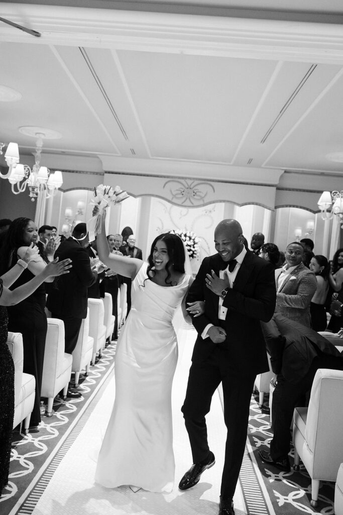 Black and white photo of a bride and groom walking back down the aisle as husband and wife after their Wynn Las Vegas Lavender Salon ceremony. 