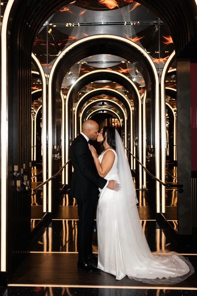 Bride and groom kissing in a mirrored walkway at Wynn Las Vegas. 