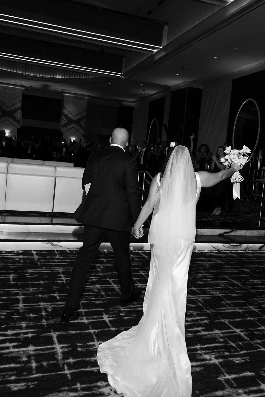 Black and white photo of a bride and groom entering their Wynn Las Vegas wedding reception.