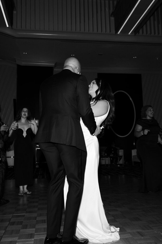 Black and white photo of the bride dancing with a family member. 
