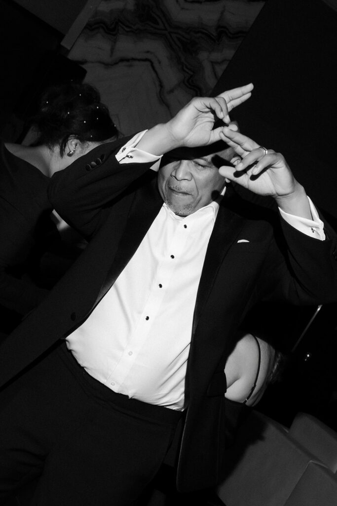 Black and white photo o a wedding guest dancing during the reception. 