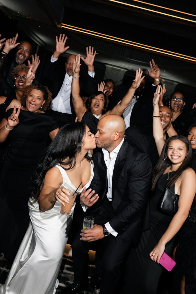Bride and groom kissing during a group shot.