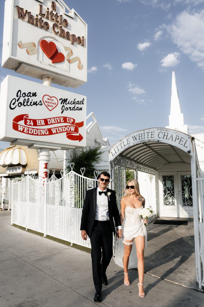 Bride and groom walking outside of The Little White Wedding Chapel.