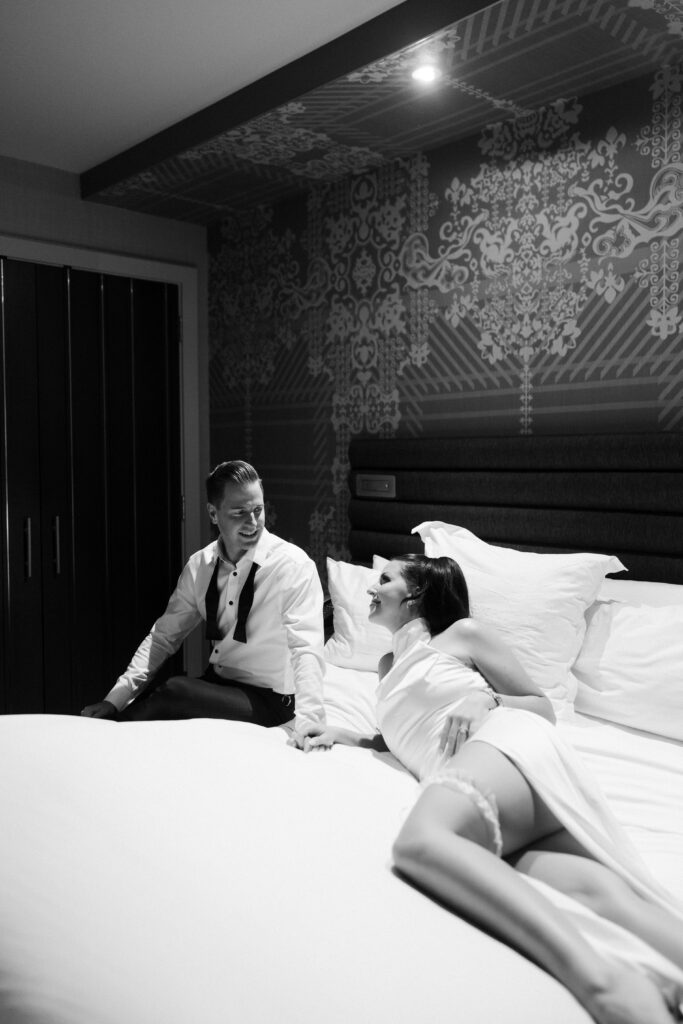 Bride and groom laying on their bed together for their luxury elopement photos. 