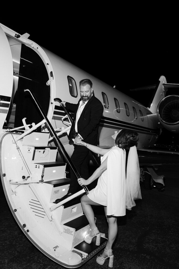 Black and white photo of a bride and groom walking up into their private jet for their luxury elopement photos. 