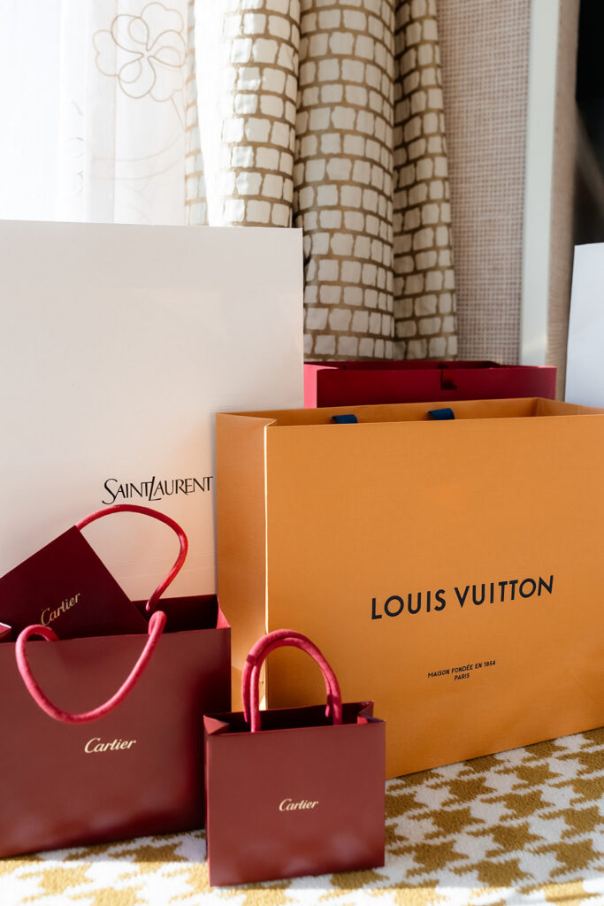 Luxury elopement details with Louis Vuitton, Cartier, and Saint Laurent shopping bags in a Wynn Las Vegas suite.