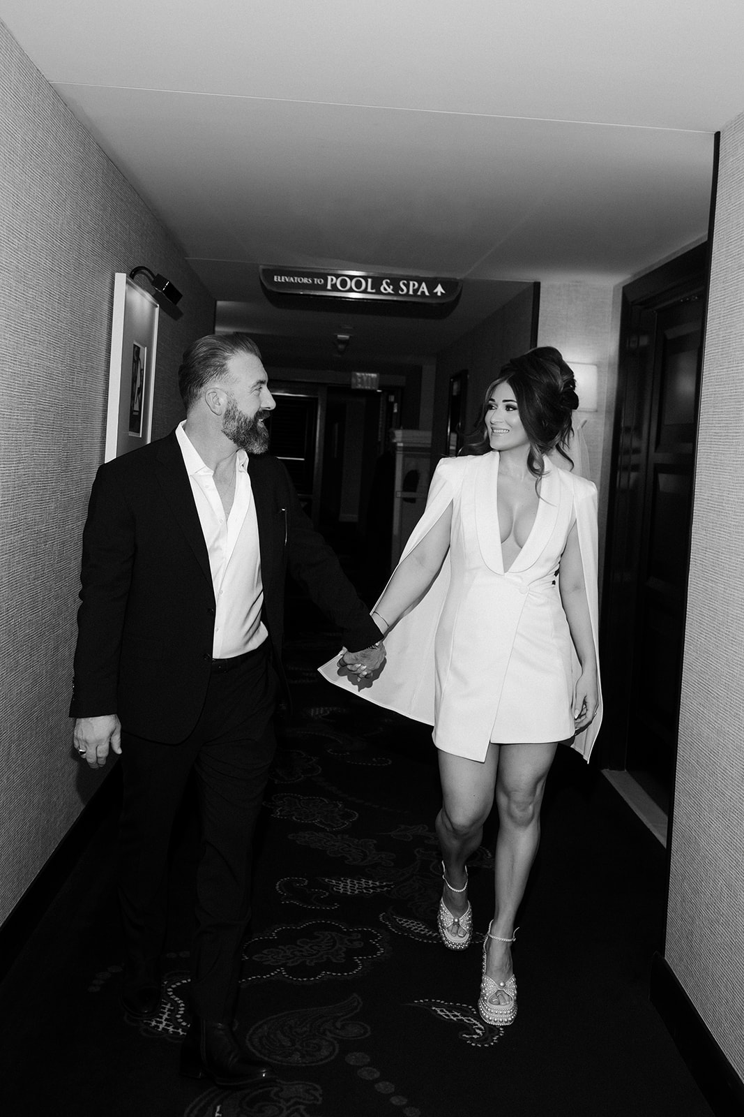 Bride and groom walking hand in hand through a Wynn Las Vegas hallway during their luxury elopement.