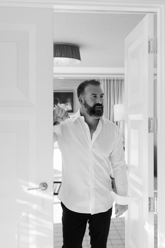 Groom getting ready in a white shirt inside a Wynn Las Vegas suite during a luxury elopement.