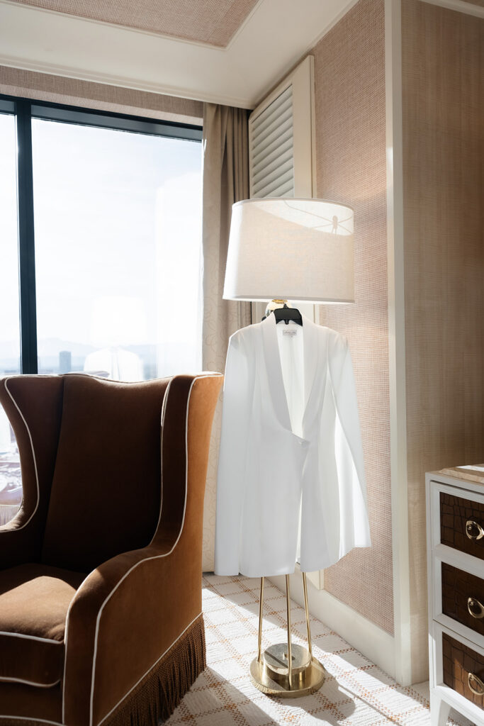 Bride’s white blazer dress hanging in a sunlit Wynn Las Vegas suite before a luxury elopement.
