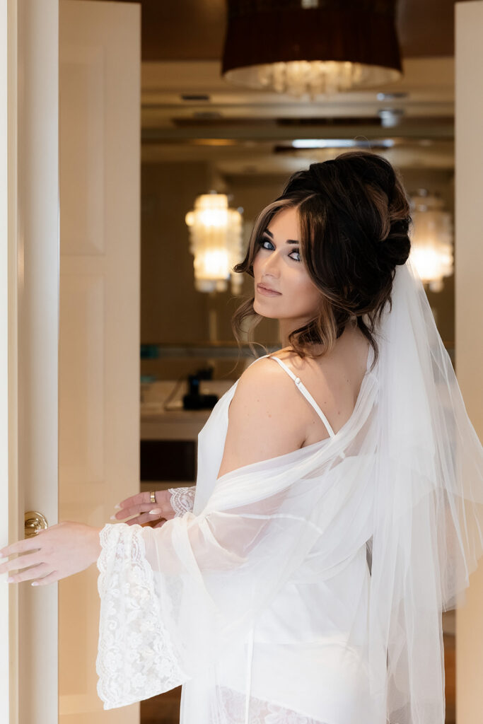 Bride getting ready in a lace robe and veil inside a Wynn Las Vegas suite during a luxury elopement.
