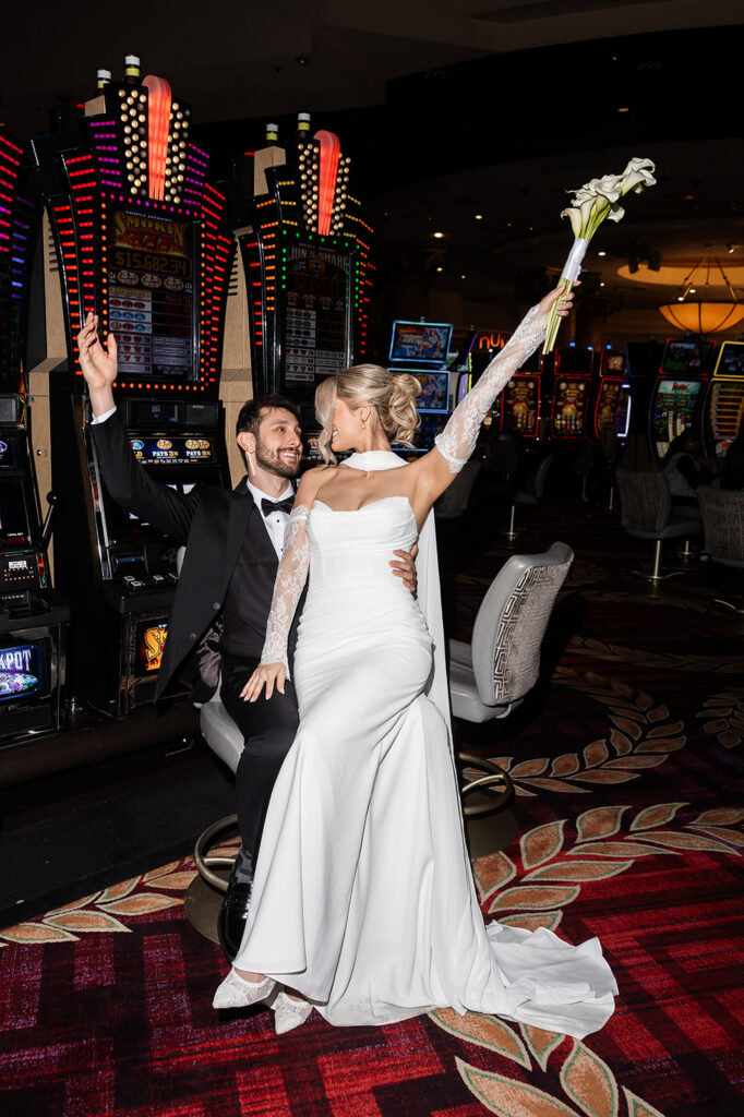 Newlyweds celebrating in front of slot machines during their Caesars Palace casino portraits.