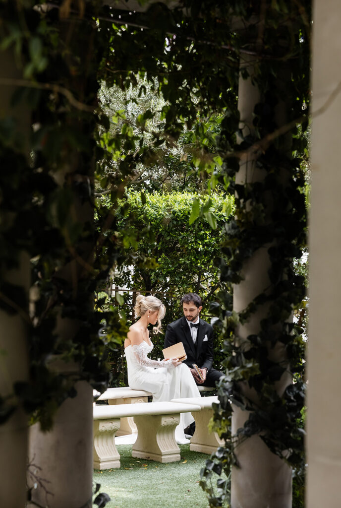 Newlywed bride and groom sitting together on garden benches at Caesars Palace after their ceremony.
