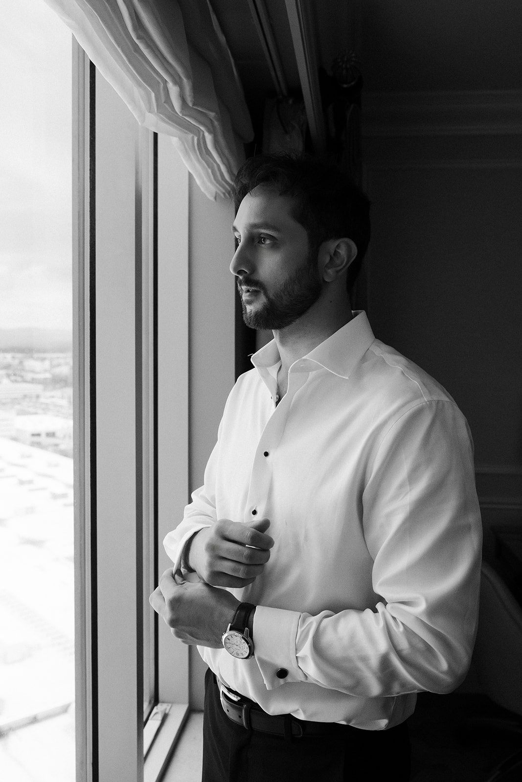 Groom getting ready by the window at Caesars Palace before the Las Vegas wedding ceremony.