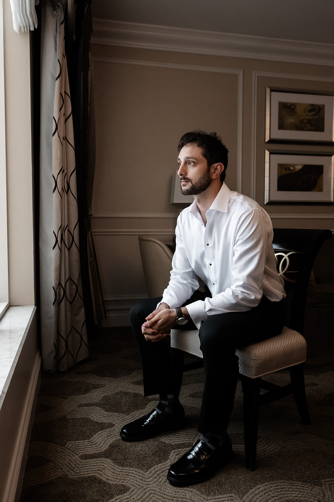 Groom sitting by the window finishing getting ready at Caesars Palace before the wedding ceremony.