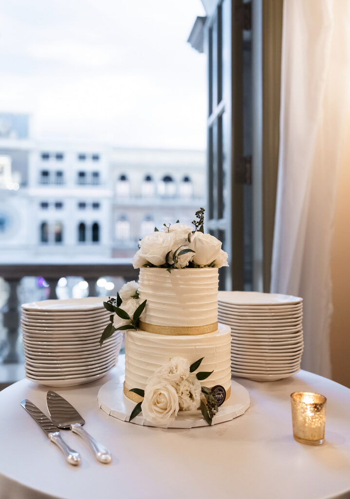Wedding cake with white florals displayed during the Canaletto Las Vegas wedding reception.