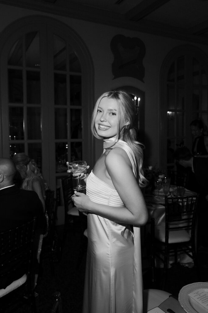 Black and white flash wedding reception photo of a guest posing with a drink in hand during a Canaletto Las Vegas wedding reception.