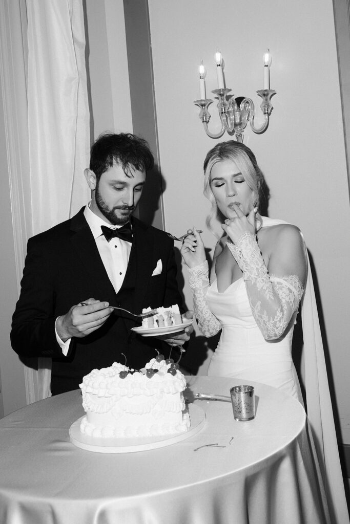Black and white photo of a bride and groom cutting into their cake during their Canaletto Las Vegas wedding reception.