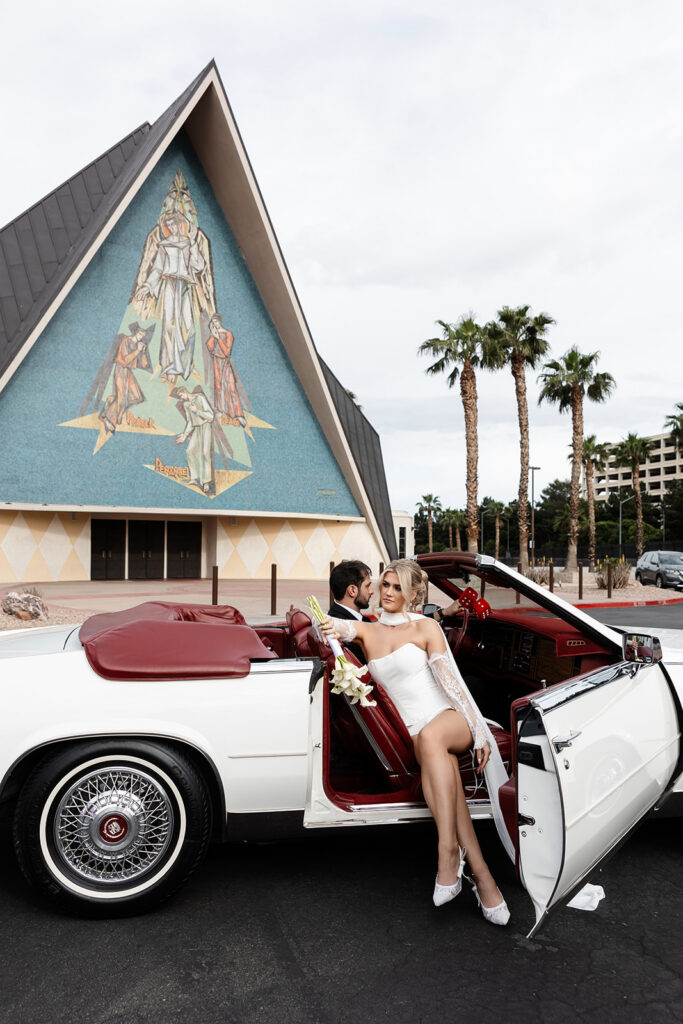 Bride and groom sitting inside a classic white convertible outside of Guardian Angel Cathedral in Las Vegas.