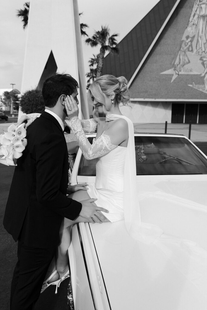 Black and white photo of a bride sitting on a classic convertible outside of Guardian Angel Cathedral in Las Vegas.
