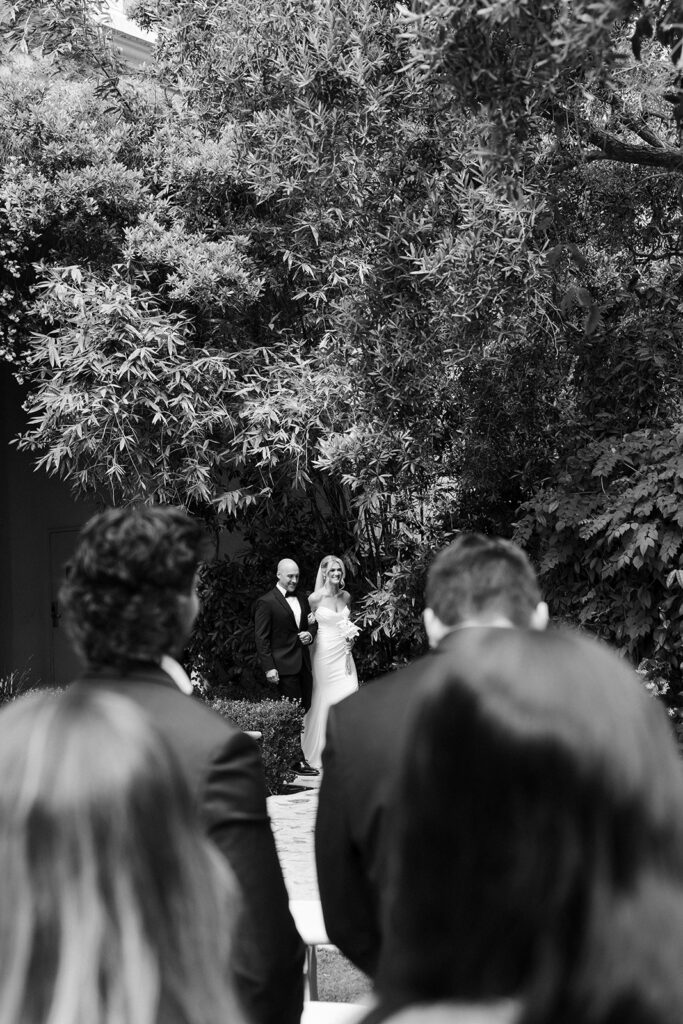 Bride walking down the aisle toward the groom during their outdoor ceremony at the Venus Garden Chapel at Caesars Palace.