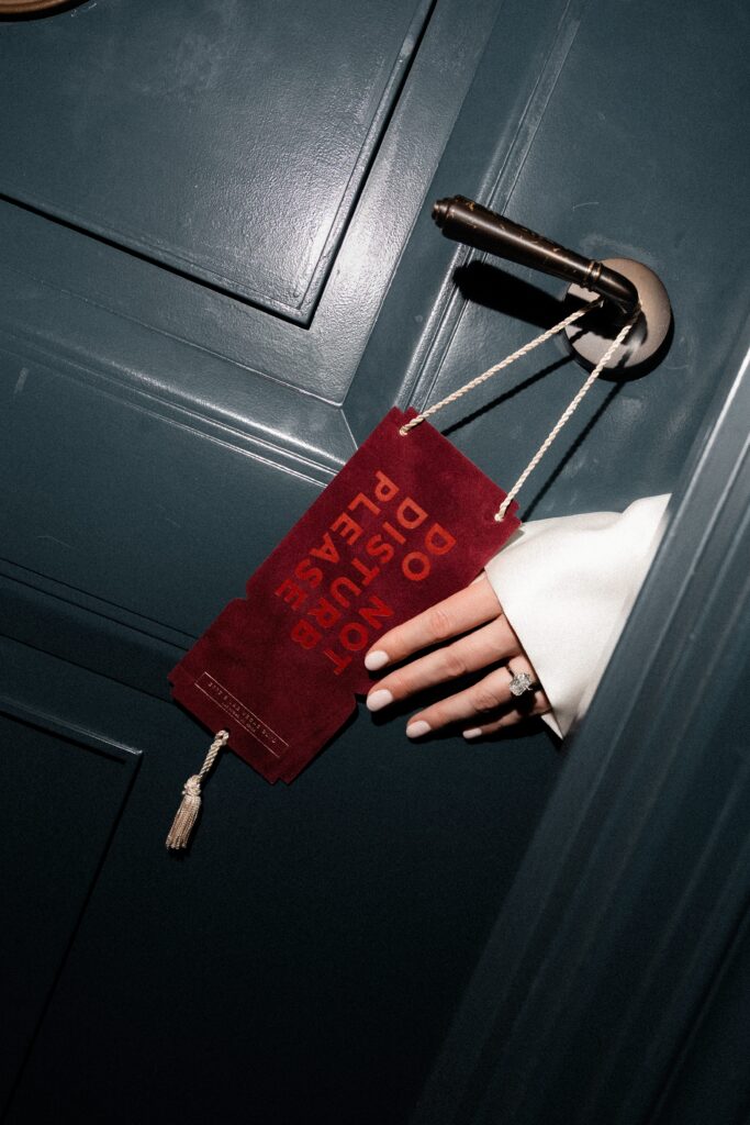 Bride holding a do not disturb sign on her hotel room door. 