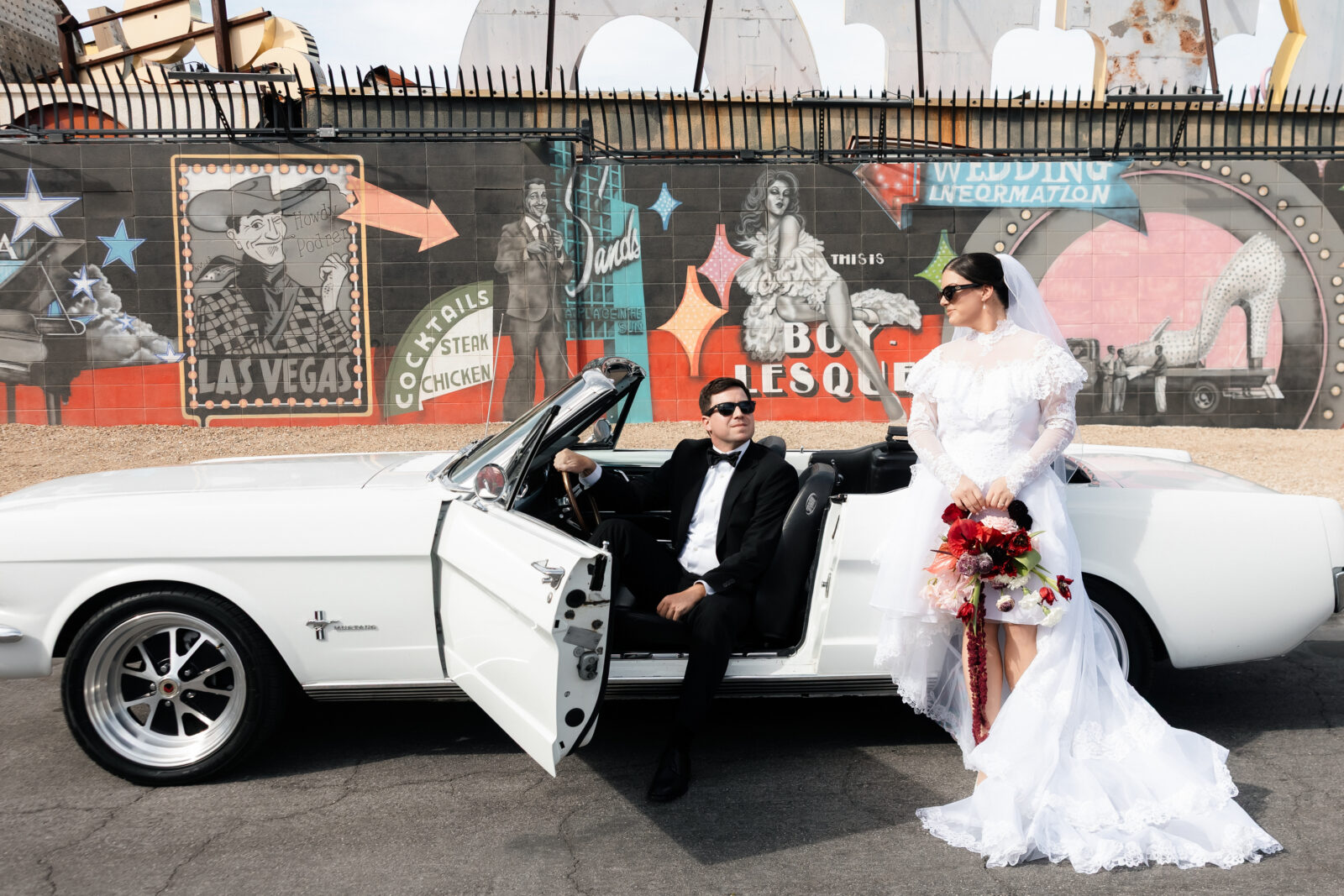 Bride and groom posing with a classic white convertible for their Las Vegas wedding photos.