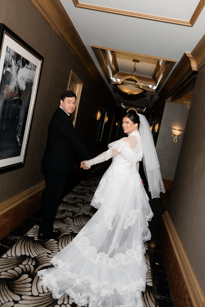 Bride and groom walking down the hallway of their hotel room.