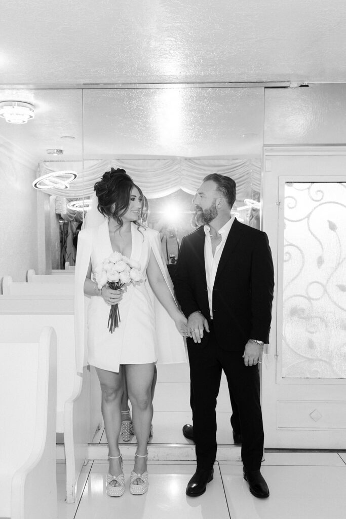 Black and white photo of a bride and groom walking down the aisle to the altar. 