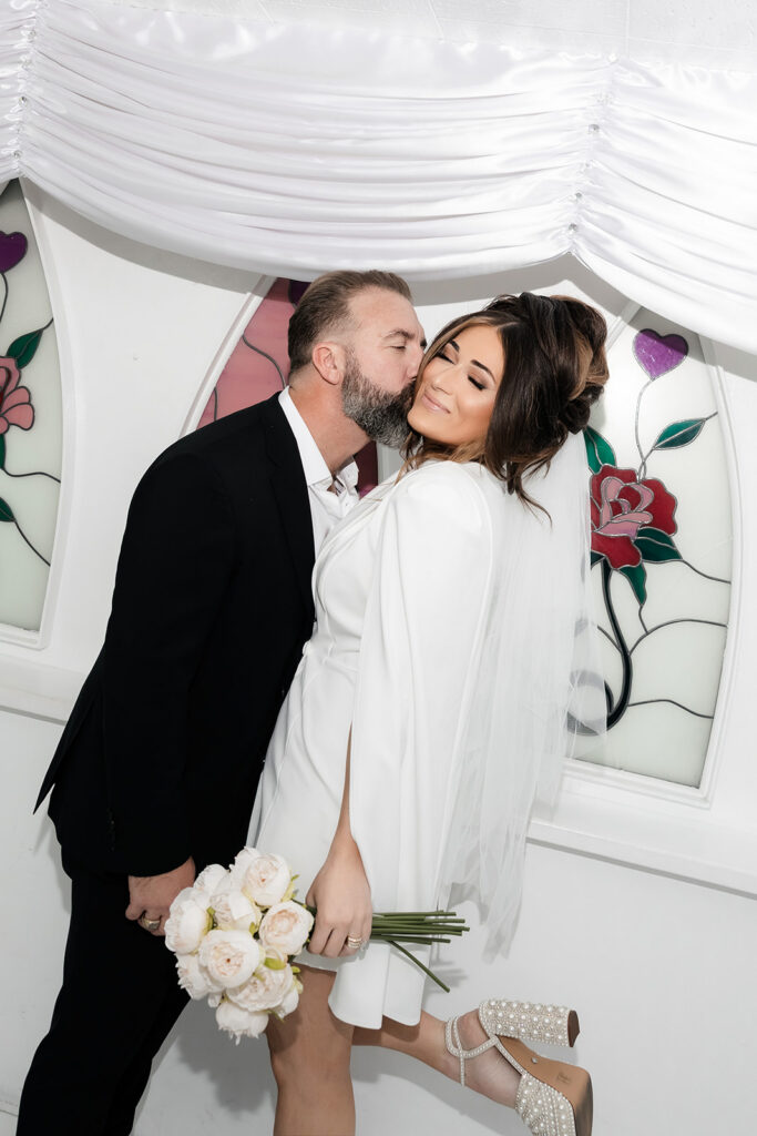 Bride and groom kissing in the original Little White Chapel. 